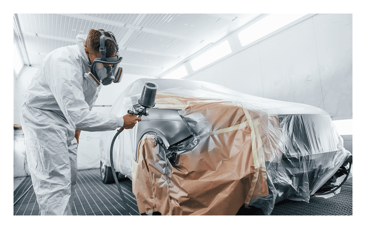 Worker painting car in protective gear